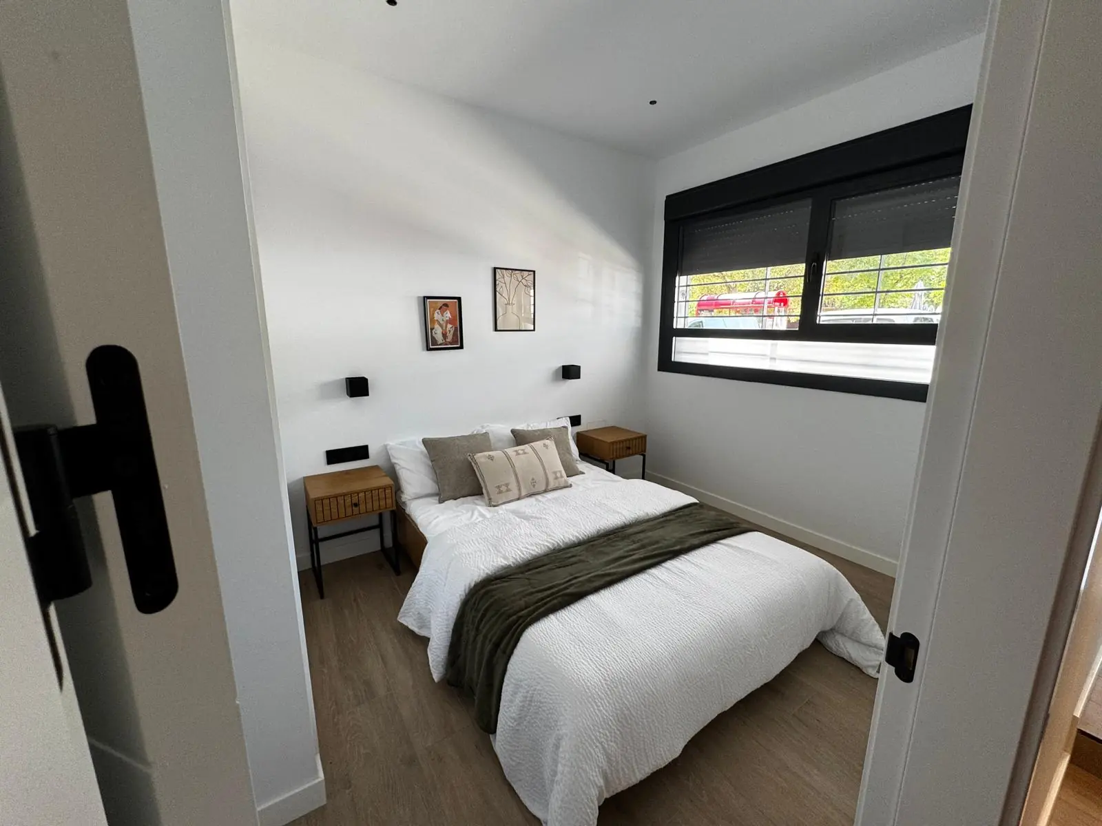 Dormitorio terminado con carpintería negra y suelo de madera