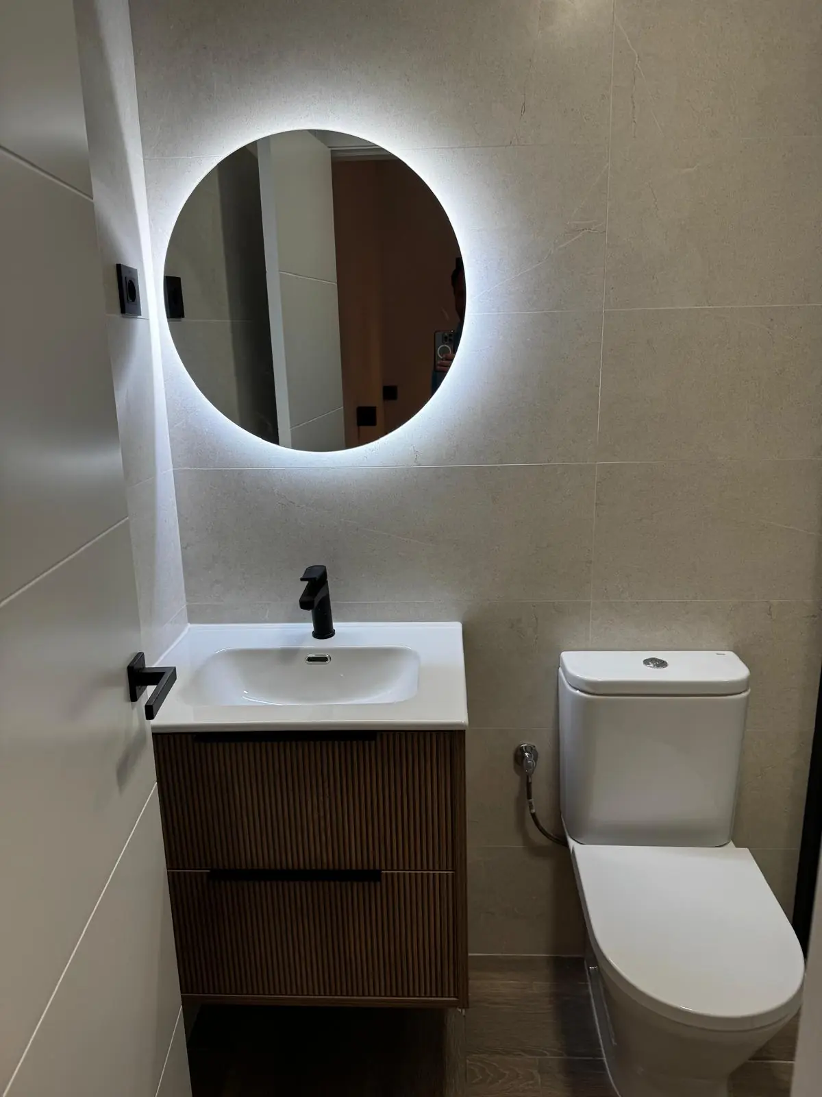 Baño compacto con espejo retroiluminado y grifería negra