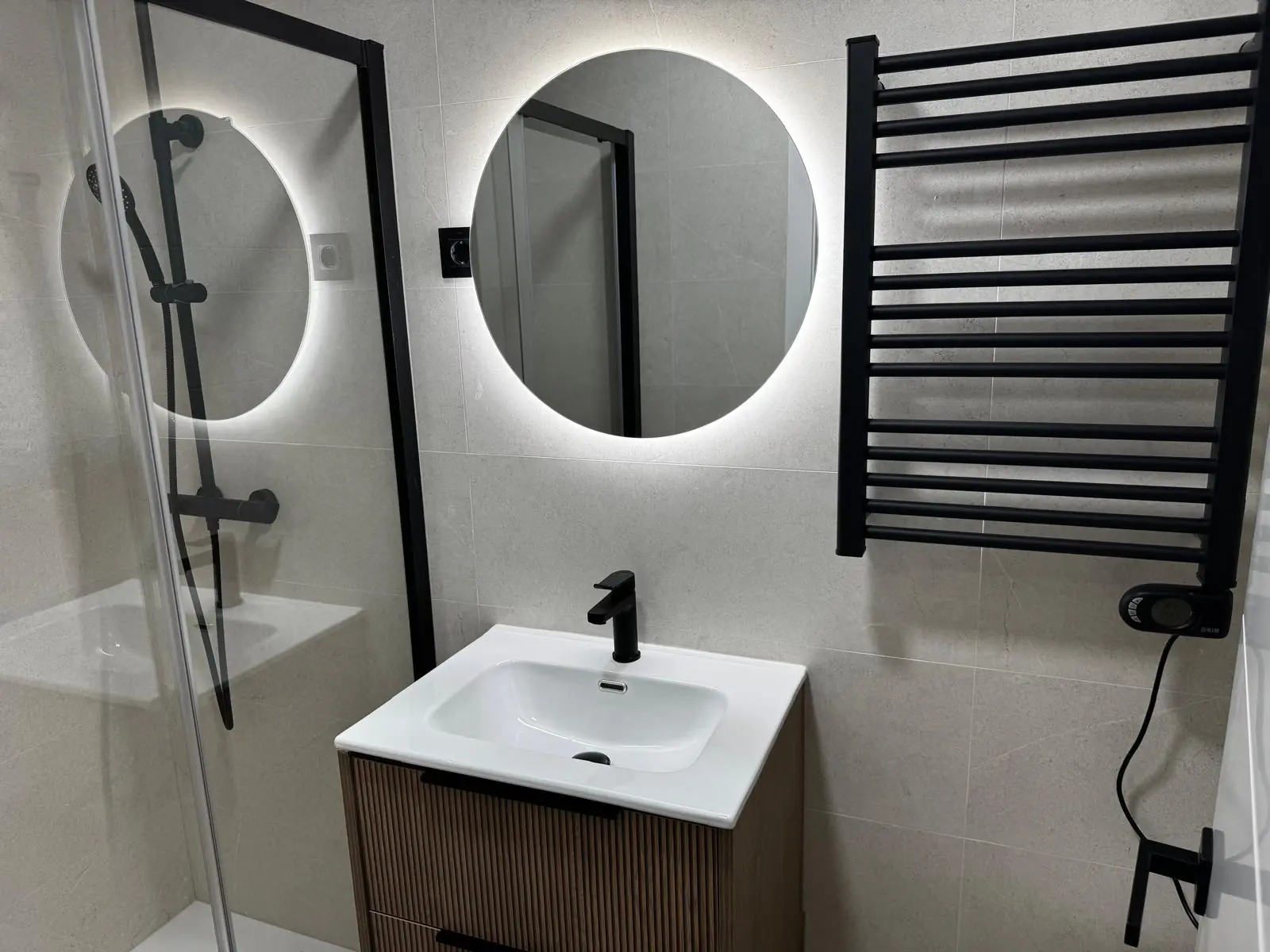 Baño terminado con ducha y espejo circular retroiluminado